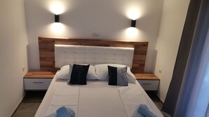 A neatly made bed with white linens and two pillows, two bedside tables with lamps, and a wooden headboard. - Apartment in Lopar with Terrace, Air condition, WIFI (4620-1) (Lopar)