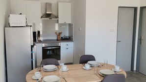 A modern kitchen with a dining area. It includes a refrigerator, stove, microwave, and cabinets. There are four chairs around a wooden table set for dining. - Apartment in Lopar with Terrace, Air condition, WIFI (4620-1) (Lopar)