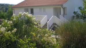 Une maison à deux étages, avec un toit recouvert de tuiles rouges, des murs extérieurs blancs et un petit porche.