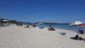 A beach with umbrellas, sun loungers, and people relaxing.