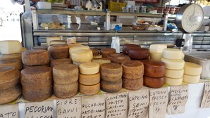 A variety of cheeses displayed on a counter with labels indicating names and prices.