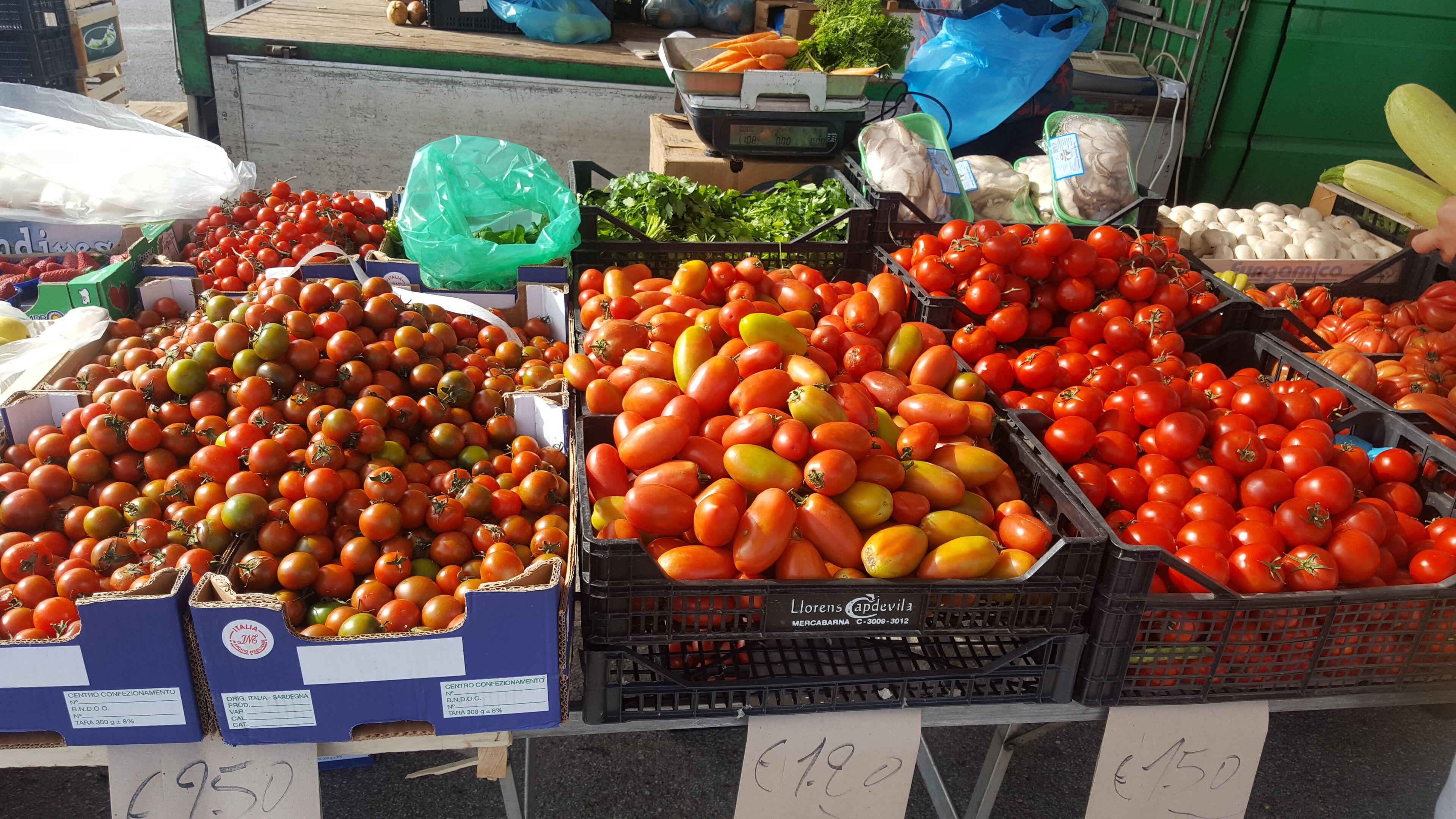 A market stall with various vegetables including tomatoes and artichokes.