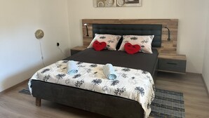 Ein modernes Schlafzimmer mit einem Holzkopfteil, zwei Nachttischen, einem Bett mit floralem Bettzeug und einem Wandbild über dem Bett.