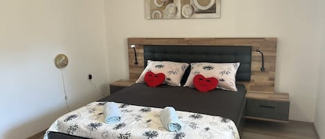 Ein modernes Schlafzimmer mit einem Holzkopfteil, zwei Nachttischen, einem Bett mit floralem Bettzeug und einem Wandbild über dem Bett.