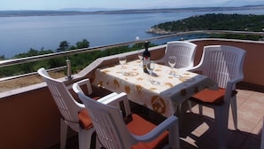 Una terraza con una mesa preparada para dos, con vistas al agua y vegetación.