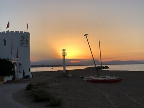 A coastal scene with a lighthouse, a white building with flags, and a row of boats on the beach. - T-1118, Casa Blanca, newly renovated villa with many extras (Els Poblets)