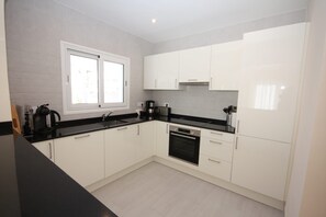 A modern kitchen with white cabinets, a black countertop, a built-in oven, and a window providing natural light. - T-1118, Casa Blanca, newly renovated villa with many extras (Els Poblets)
