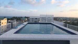 A rooftop swimming pool with a view of the sea and surrounding buildings. - Laguna Hotel (San Pedro)