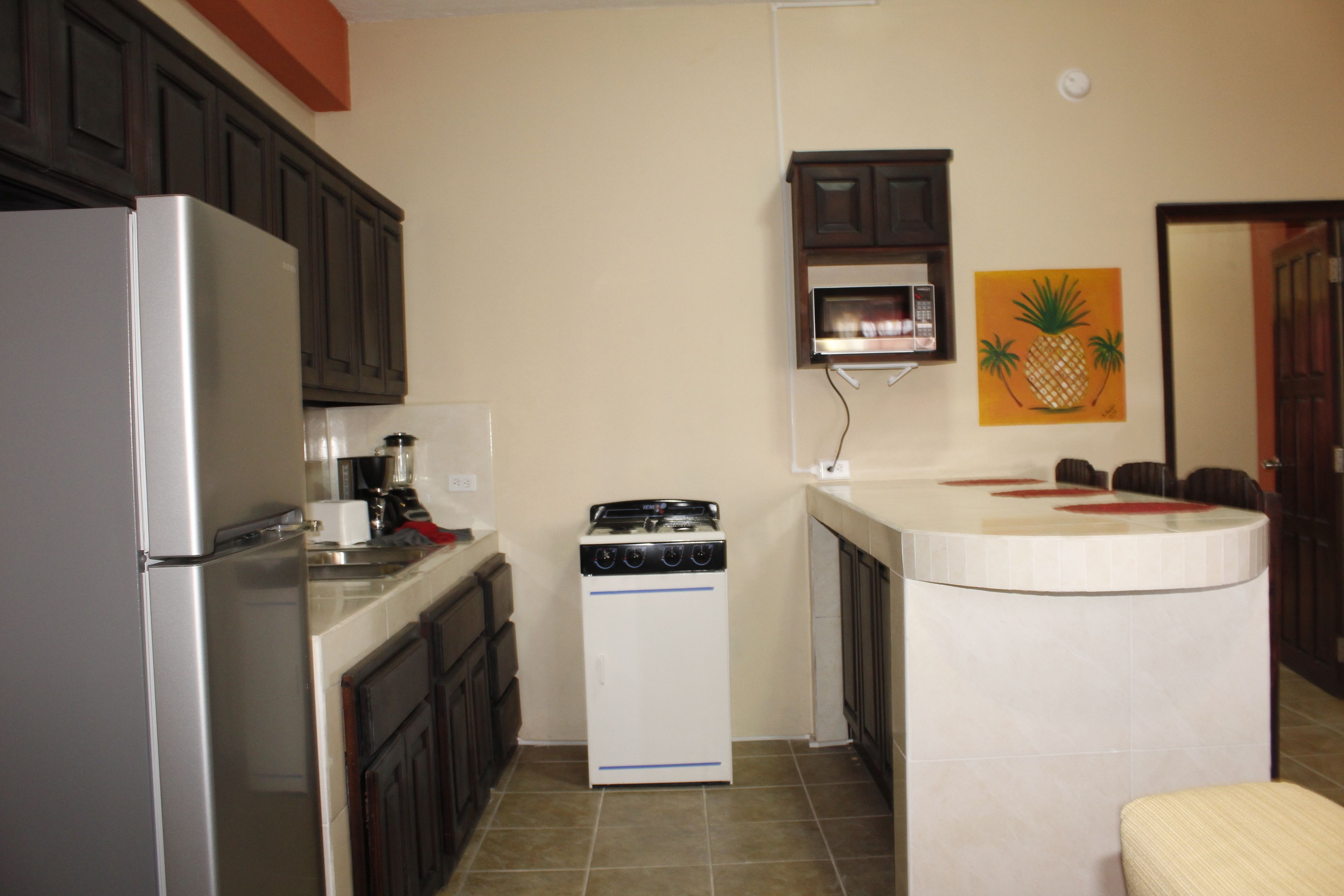 A compact kitchen with a refrigerator, stove, microwave, and a small dining area with a table and chairs.