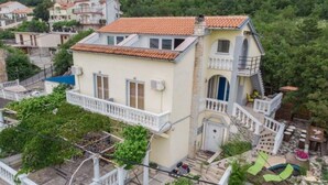 A two-story house with a balcony, a small garden, and a staircase leading to the upper floor.