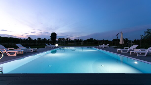 A swimming pool with lounge chairs and umbrellas, surrounded by trees and a clear sky. - Country House Campofiore (Pontelongo)