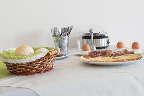 A breakfast setup with a basket of eggs, a plate of ham and cheese, a coffee maker, and a set of utensils. - Country House Campofiore (Pontelongo)