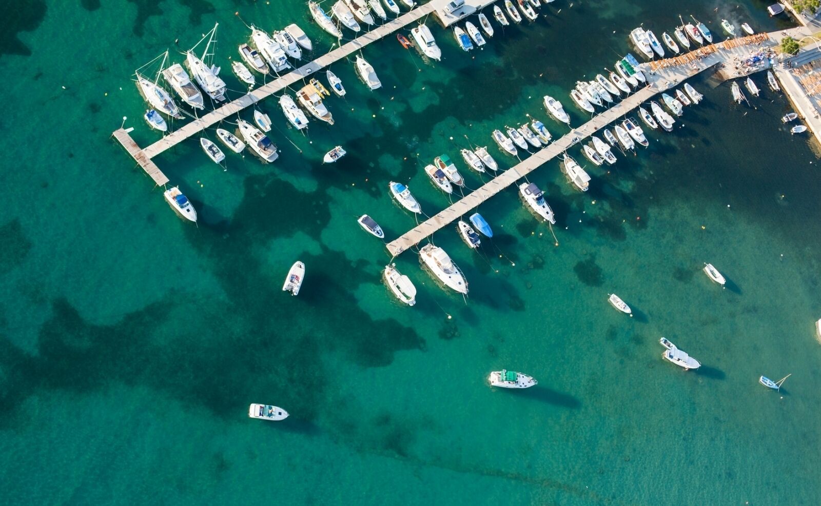 An aerial view of a marina with numerous boats docked at piers.