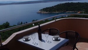 A terrace with a table set for two, overlooking a body of water and a distant shoreline. - Apartment in Dramalj with Seaview, Balcony, Air condition, WIFI (4623-12) (Dramalj)