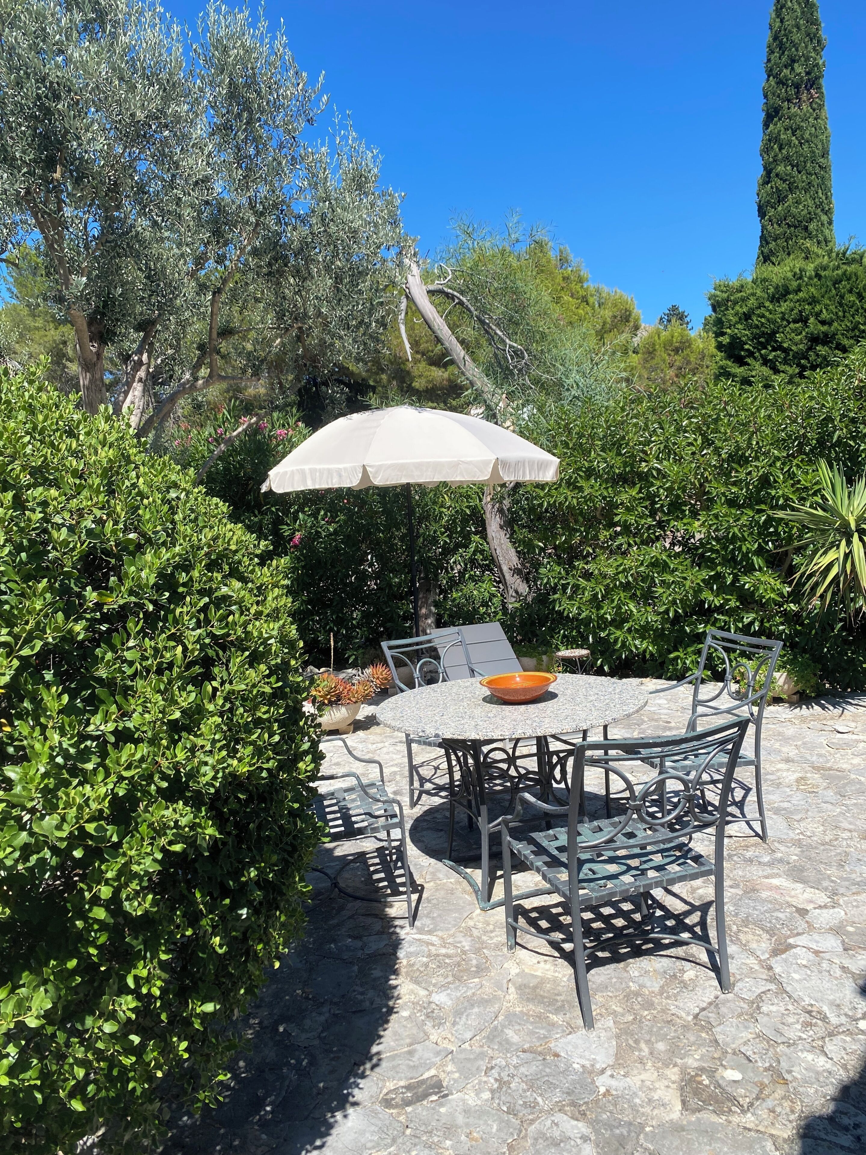 An outdoor patio with a round table, chairs, and a white umbrella.