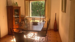 A dining area with a wooden table, chairs, a cabinet, and a window with curtains. - Beautiful, quietly located vacation home in Bon Aire near Alcudia with sea views (Mal Pas-Bon Aire)