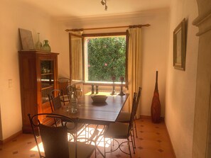 Ein Essbereich mit Holztisch, Stühlen, einem Schrank und einem Fenster mit Vorhängen.