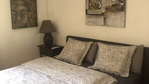 Un dormitorio con una cama, una mesita de noche, una lámpara y dos cuadros en la pared.