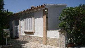 Un edificio con entrada empaveda de piedra, fachada blanca y tejado de tejas.