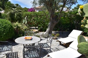 A patio area with a round table, chairs, and lounge chairs.