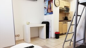 A modern kitchen with a microwave, a coffee maker, and a small table with a remote control.