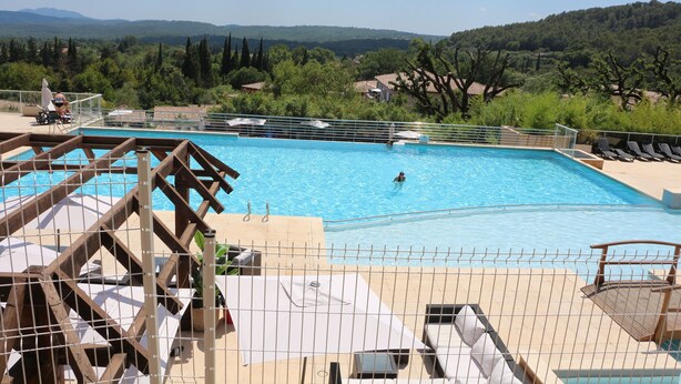 A swimming pool with a view of the surrounding landscape, including trees and distant hills.