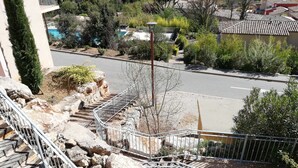 A residential area with a road, a swimming pool, and a view of distant houses and greenery.