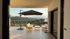 A balcony with a view of mountains, a table, two chairs, and an umbrella. - Villa sea view in Pinarello - near Porto-Vecchio (ZONZA)