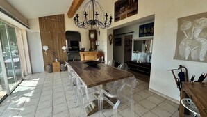 Uma sala de jantar com uma mesa de madeira e cadeiras transparentes, um candelabro e um painel de madeira.