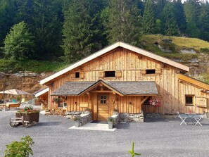 Eine Holzhütte mit geneigtem Dach, Stein Fundament und einem Schotterweg.