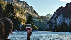En person i en jacuzzi med et bjergrigt landskab i baggrunden.