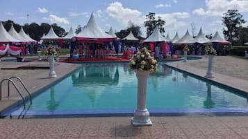 Una piscina al aire libre, sombrillas, sillones reclinables de piscina