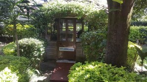 A small wooden structure labeled "DREAMMoods" with a glass door, surrounded by lush greenery and a red pathway leading to it. - Lanet Matfam Resort (Nakuru)