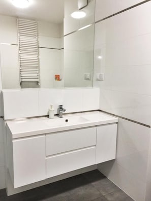 A modern bathroom with a white vanity, a mirror, and a towel rack. - Apartamenty Zajezdnia MTP (Poznan)