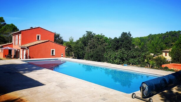 A swimming pool with a red building in the background, surrounded by greenery. - EXCEPTIONAL site: SPACIOUS VILLA 8 BEDS, SWIMMING POOL 15x5M, SAUNA (Le Val)