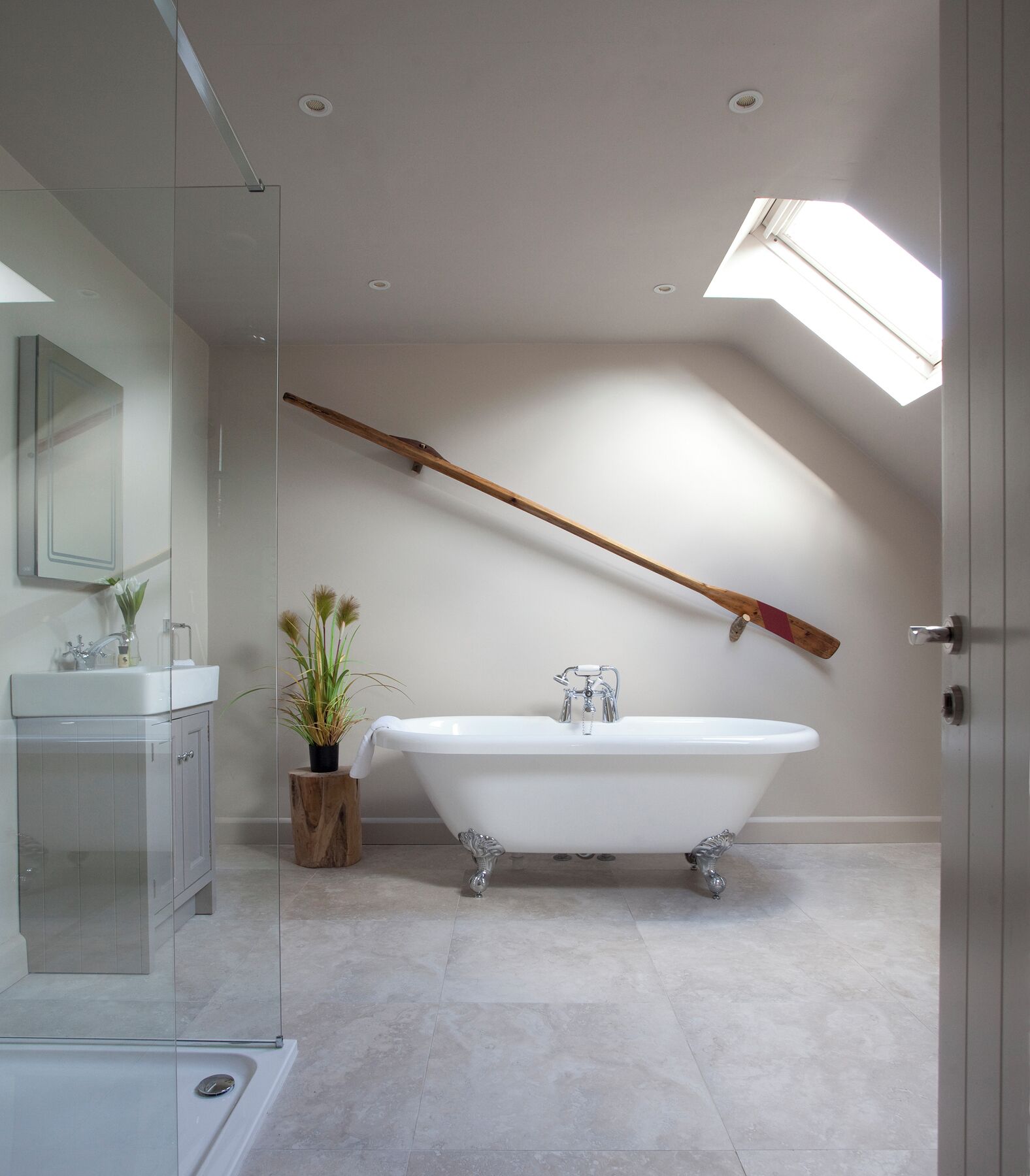 A modern bathroom with a freestanding bathtub, a glass shower enclosure, and a skylight.