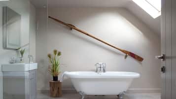 Ein modernes Badezimmer mit einer freistehenden Badewanne, einer Glasdusche und einem Oberlicht.