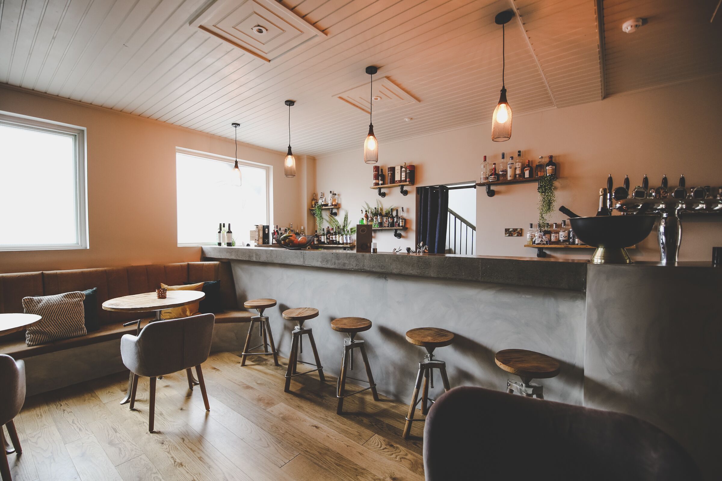 Een bar met houten krukken, een bar en flessenkasten.