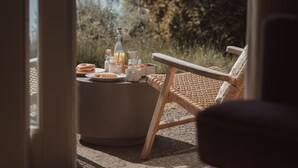 Una habitación con vistas a un lago, una mesa de comedor con comida y bebidas, y una silla de mimbre.