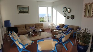 A living room with a sofa, two armchairs, a coffee table, and a TV. There is a window with a view of the sea. - 3 Rooms Apartment 65 m² + Terrace 28 m². 4 beds. Residence with Pool (Bandol)