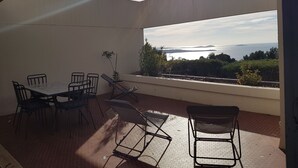 An outdoor patio with a table and chairs, a view of the sea, and a plant. - 3 Rooms Apartment 65 m² + Terrace 28 m². 4 beds. Residence with Pool (Bandol)
