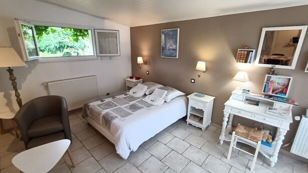 Een slaapkamer met een bed, nachtkastjes, een stoel, een bureau en een radiator.