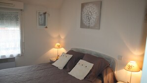 A neatly made bed with brown bedding, two bedside lamps, and a window with blinds.