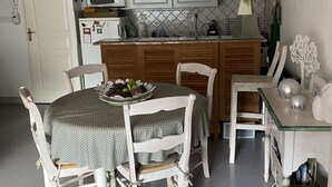 A compact kitchen with white cabinets, a microwave, and a small dining area with a table and chairs.