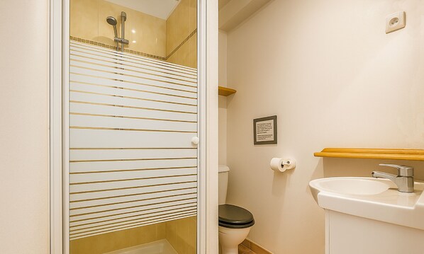 Une salle de bain avec des toilettes, un lavabo et une douche.