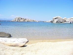 Une plage avec une eau claire, de gros rochers et un bateau.