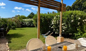 A patio with a pergola, outdoor seating, and a table set for two with a drink.