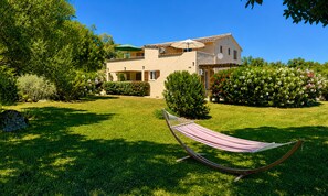 A house with a garden, a hammock, and a clear blue sky.