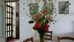 Una mesa de comedor con un florero, dos cuadros en la pared y una puerta con felpudo.