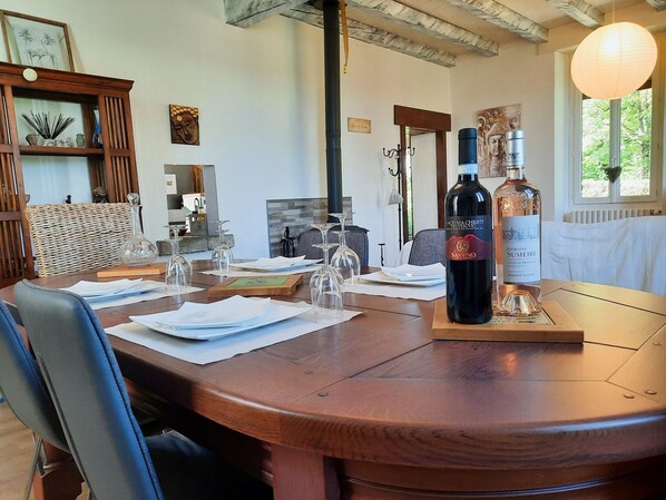 A dining table set with wine glasses, a bottle of Domaine Sumeire wine, and a wooden chair.